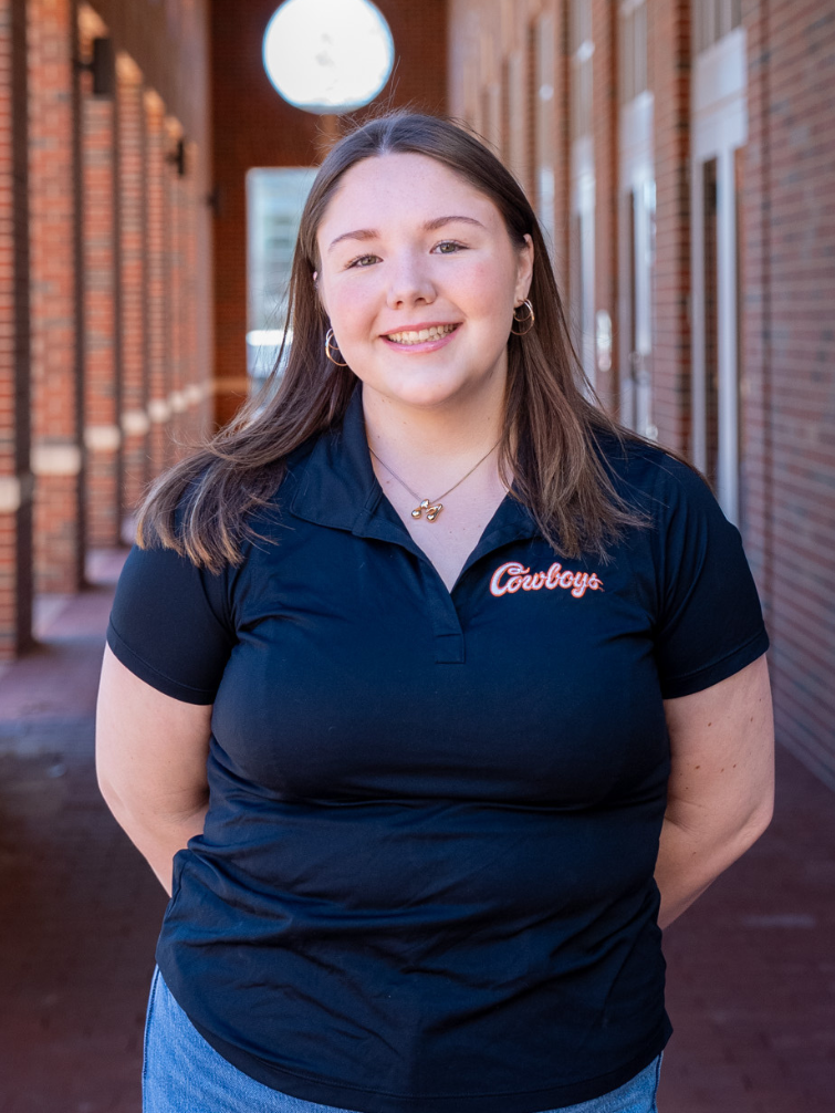 student posing behind ConocoPhillips OSU Alumni Center