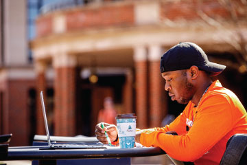 Male student working outside at a table