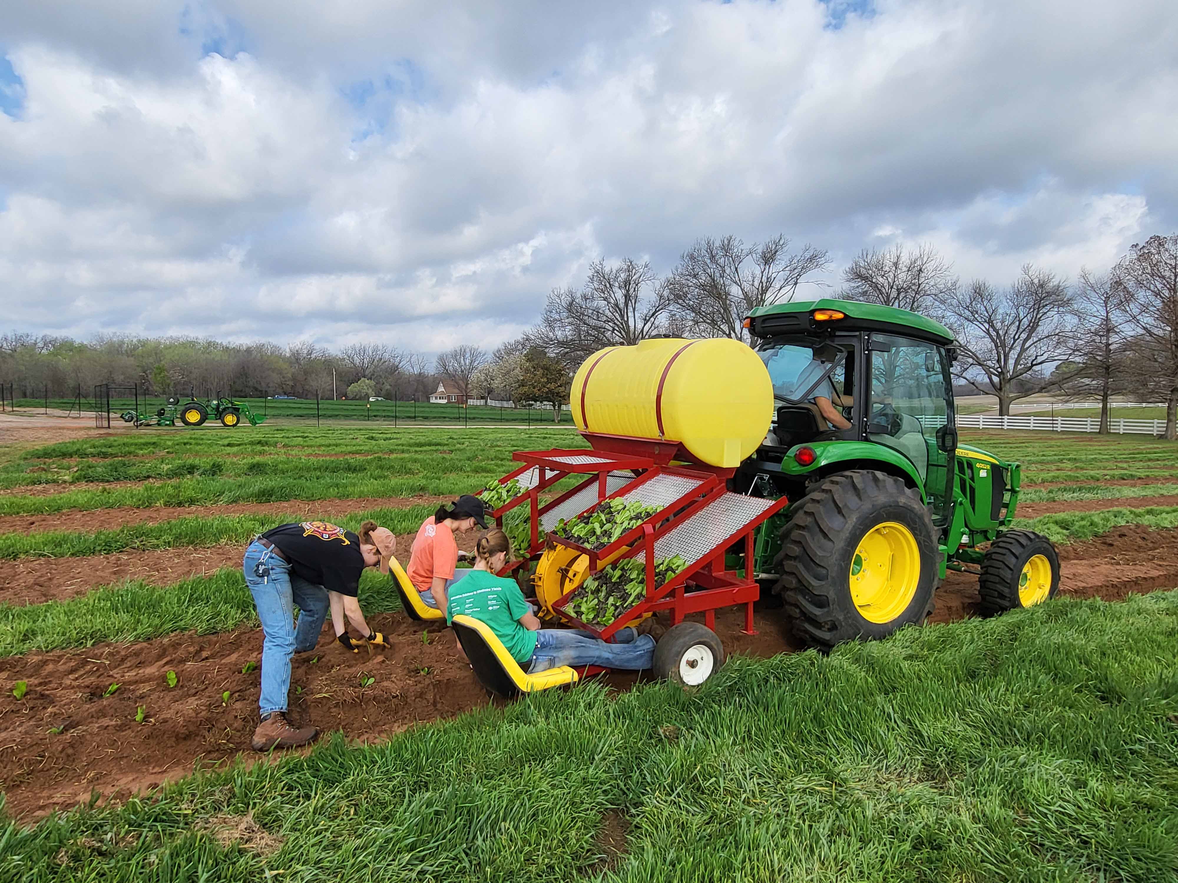 Student workers on machinery working on farm